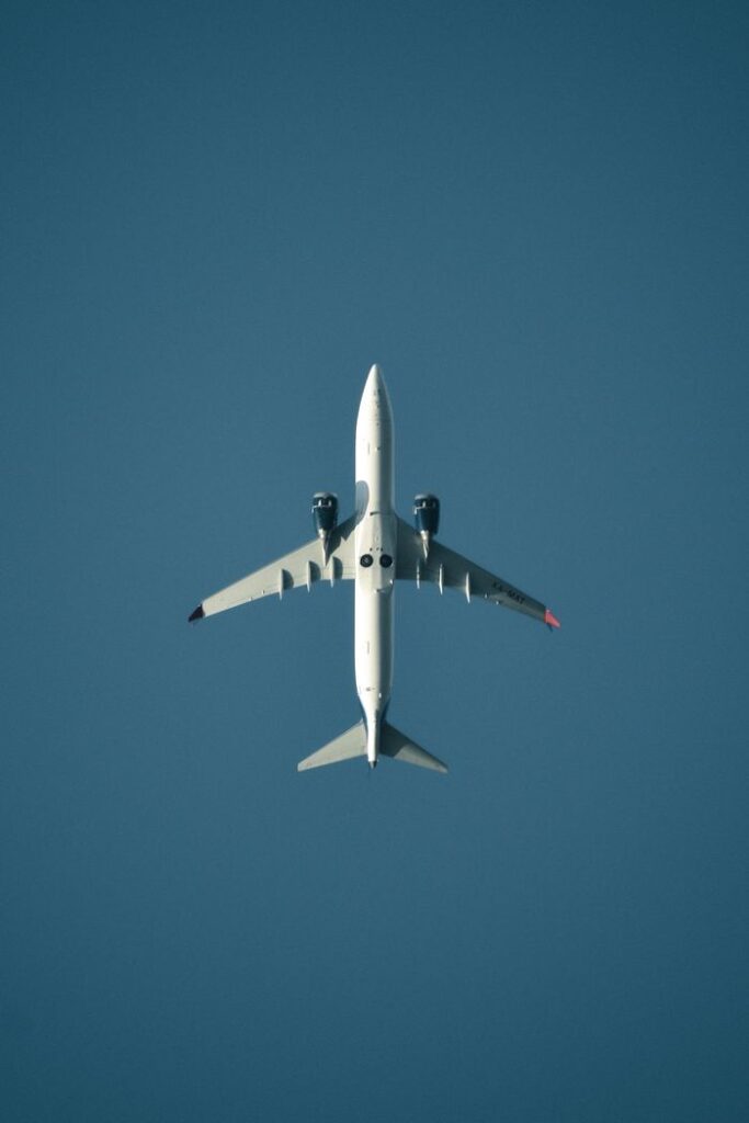 A sleek airplane captured from below soaring in a clear blue sky, showcasing aerodynamics.