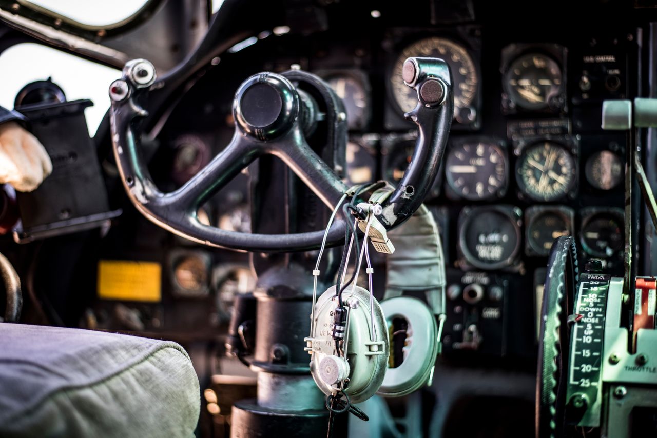 Close-up of a vintage aircraft cockpit showing controls, dials, and headphones in rich detail.