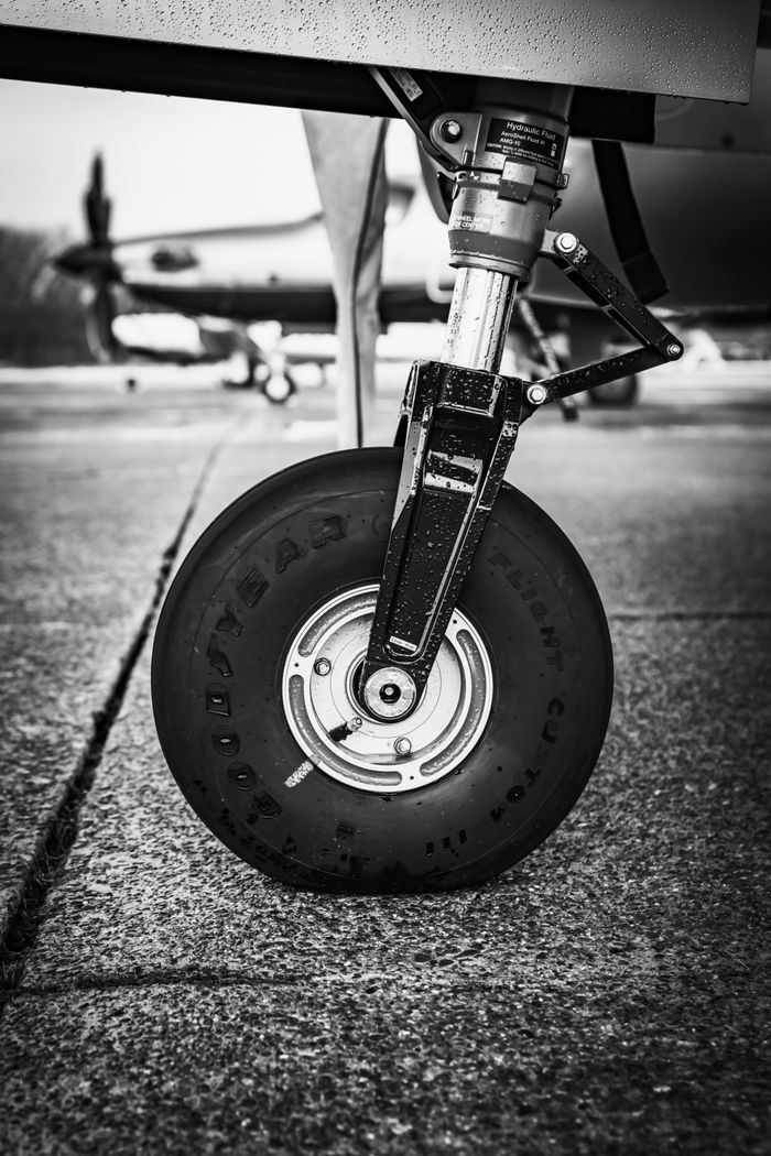 Detailed close-up of a landing gear wheel on an aircraft, in black and white.