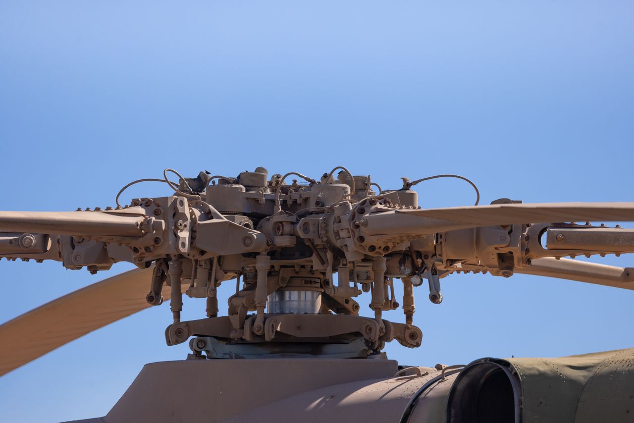 Detailed view of helicopter rotor blade assembly under clear blue sky.